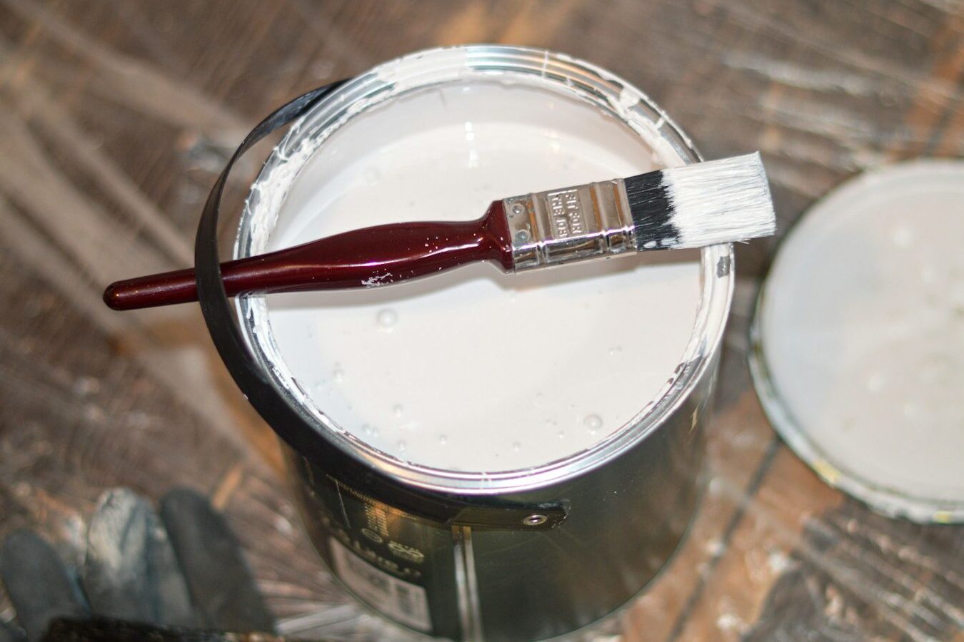 red handle paint brush in white paint bucket